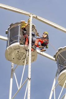 Two workers in protective clothing carry out inspections on a Ferris wheel, fire brigade exercise