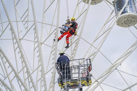 Firefighters rescue person by abseiling from Ferris wheel, fire brigade exercise for gondola
