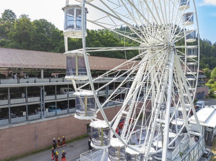 View of a Ferris wheel in a city, firefighters on site, fire brigade exercise for gondola rescue,