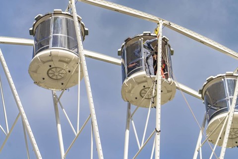 Detailed view of two giant wheel cabins in front of a clear blue sky, fire brigade exercise for