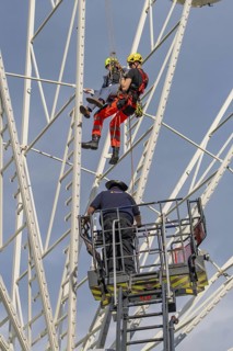 Firefighters on a rescue mission on a Ferris wheel with crane support, fire brigade exercise for