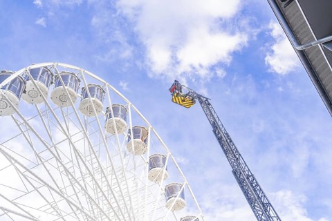 Lifting platform reaches the top of the Ferris wheel in a clear sky, fire brigade exercise for