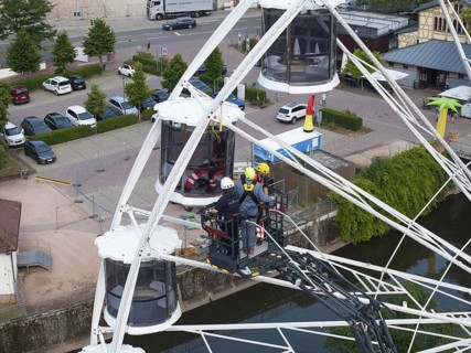 Firefighters during a rescue exercise on a Ferris wheel in an urban environment with parked cars,