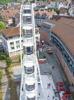 Rescue operation on a Ferris wheel with emergency vehicles in an urban setting with red roofs, fire