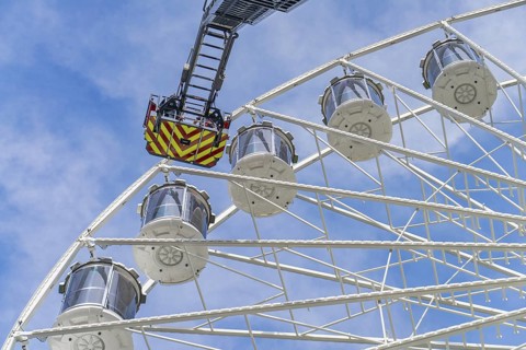 Fire brigade operation on a large Ferris wheel under a blue sky, fire brigade exercise for gondola