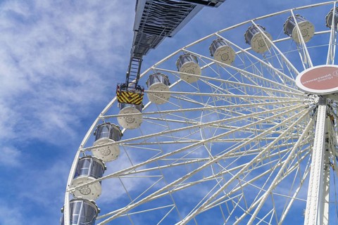 A fire brigade ladder extends to the Ferris wheel, which rises against the blue sky, Fire brigade