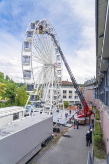 Fire brigade operation next to tall buildings with a Ferris wheel in the background, Fire brigade