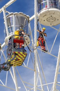 Worker with safety equipment during maintenance work on a Ferris wheel, fire brigade exercise for