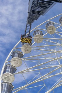 Fire brigade ladder extends against the sky to the cabins of the Ferris wheel, ready for a rescue,