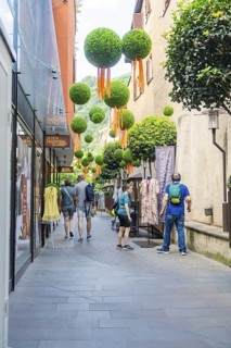 Narrow shopping street with people and decorative baubles on the faÃ§ade, Merano, South Tyrol,