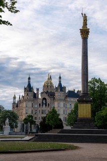 Schwerin Castle rises behind the Victory Column with golden statue, Schwerin,