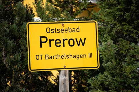 A yellow sign with the inscription Baltic resort Prerow in front of green trees, Prerow,