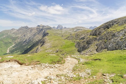 Expansive view of mountain landscape with green grass and blue sky full of clouds, Schlehrn hike,