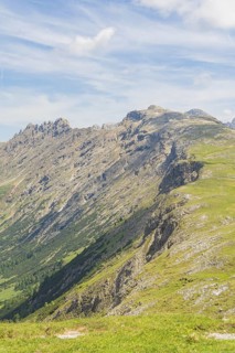 Steep mountain range with green slopes and striking sky in the background, Schlehrn hike, Alpe di
