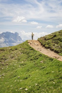 Hikers on a path in a mountainous landscape under a blue sky, Schlehrn hike, Alpe di Siusi,