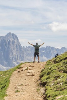 Person on a path with outstretched arms in front of a majestic mountain landscape, Schlehrn hike,