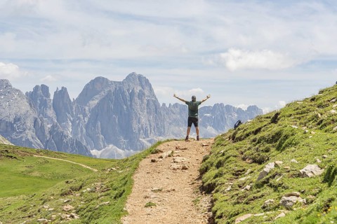 Person with raised arms on a hiking trail in front of an impressive mountain panorama, Schlehrn