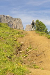 A hiker walks along a sunny nature trail, surrounded by mountainous landscape, Schlehrn hike, Alpe