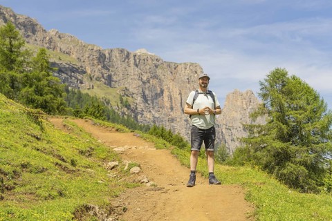 A hiker with a rucksack on a path against a rocky mountain backdrop in fine weather, Schlehrn hike,