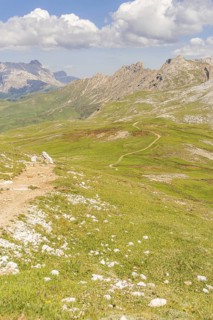 Extensive mountain landscape with winding hiking trail and clouds, hike to the Schlehrn, Alpe di