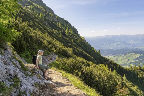 Hiker sitting on a mountain path with a view of the valley, hike to the Schlehrn, Alpe di Siusi,