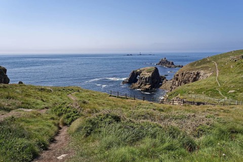 View from Land's End of the coastal footpath and the lighthouse off the coast. Land's End, the tip