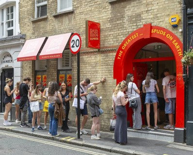 Queue line of people waiting at entrance Spud Bros Express fast-food takeaway, Soho, London,