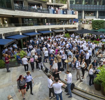 Crowd of people after work drinks outside The Botanist restaurant bar, Broadgate Circus, City of
