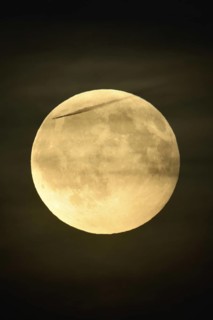 In the night sky... Full moon on an almost starry night, only a few thin clouds obscure the moon,