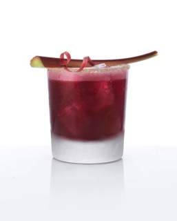 Cocktail in a tumbler on ice with rhubarb stalk as garnish against a white background, studio shot