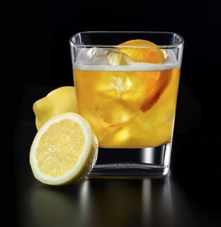 Cocktail in a tumbler on ice with orange slice and lemons as garnish against a black background,