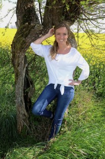 Young woman standing at an old willow tree in SkÃ¥ne County, South Sweden