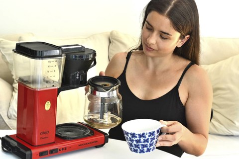 Young beautiful Southern European woman, brunette, 30 years old, reviews a coffee machine in Ystad,