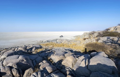 Round rocks of Kubu Island with view over the salt pan, off-road vehicle on the salt pan, Kubu