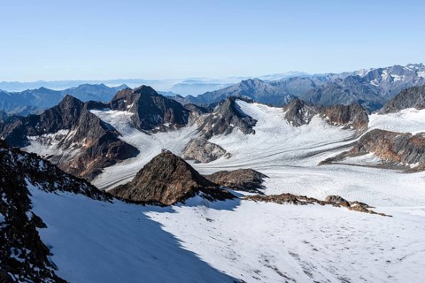 Narrow rocky ridge at the Wilder Freiger summit, picturesque high mountain landscape with snow,
