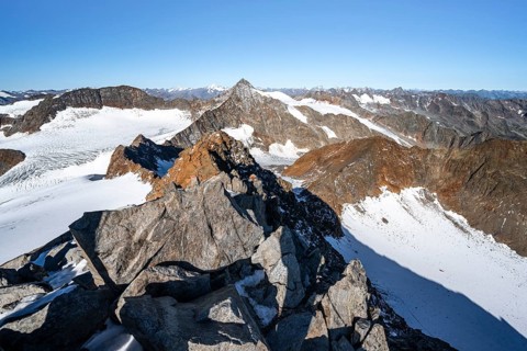 Narrow rocky ridge on the Wilder Freiger summit, picturesque high mountain landscape with snow,