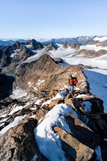 Mountaineer on a rocky ridge on the Wilder Freiger summit, behind him Signal summit and Becher