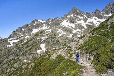 Mountaineer on hiking trail, summit of the Aiguilles rouges with snow remains, Chamonix,