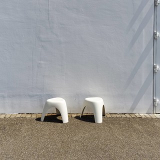 Two white plastic stools in front of a white wall, Elephant Stool, design Sori Yanagi, stackable,