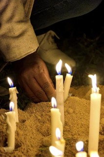 Hand placing a candle as an offering during prayers at a religious festival, Minas Gerais, Brazil