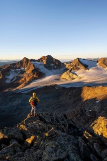 Mountaineers in front of a picturesque high mountain landscape at sunrise with alpenglow, glacier