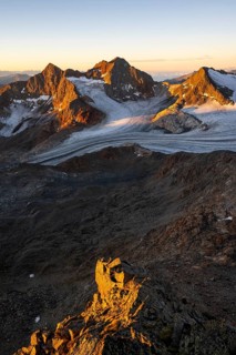 Picturesque high mountain landscape at sunrise with alpenglow, glacier and rocky mountain peaks in