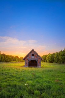 View of an open half-timbered barn standing on a pasture in the sunset, meadow, spring, awakening,