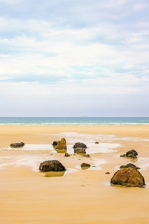 Rocks on a empty sand beach with a sea view towards the horizon in the summer, Crozon Peninsula,