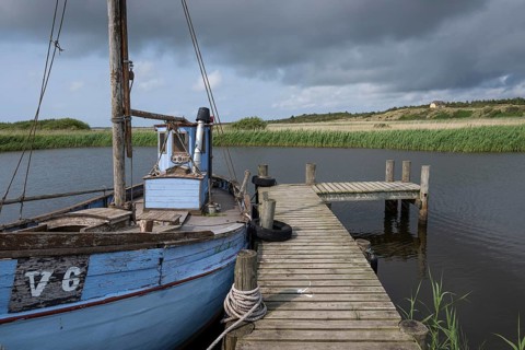 Old blue fishing boat moored at wooden jetty, RingkÃ¸bing Fjord, old fishing village Nymindegab,