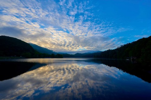 Impressive morning view with reflecting sky on a calm lake, framed by gentle mountains, summer,