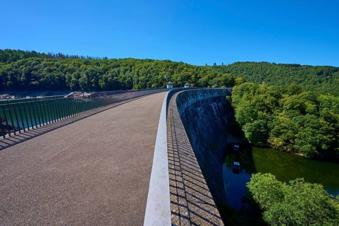 Long dam with neighbouring river and surrounding forest, clear sky, summer, Urft dam wall, Obersee,