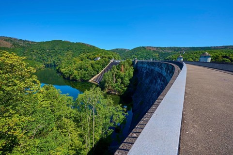 Large dam with water reservoir and lush forest under a clear sky, summer, Urft dam wall, Obersee,