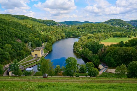 Quiet river dam surrounded by green hills and forests under a cloudy sky, summer, Rursee,