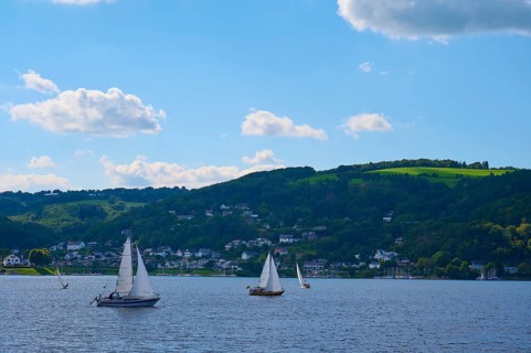 Sailing boats on a calm lake, surrounded by green hills and white cloudy sky, summer, Rursee,
